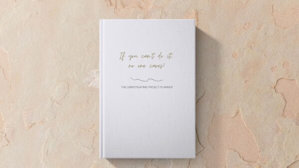 Mock up image of hardcover funny unmotivating project planner sitting on a desk. Light blue matte cover "If you can't do it, no one cares."