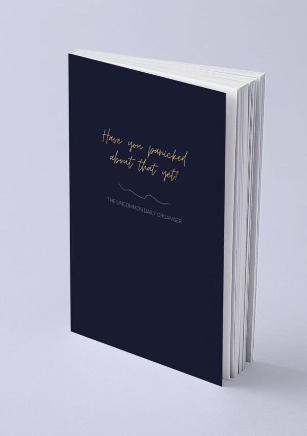 Mock up image of paperback funny unmotivating project planner sitting on a desk. Dark blue matte cover