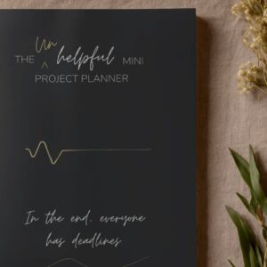 The unhelpful mini project planner. A5 mini project planner black cover mock up image.